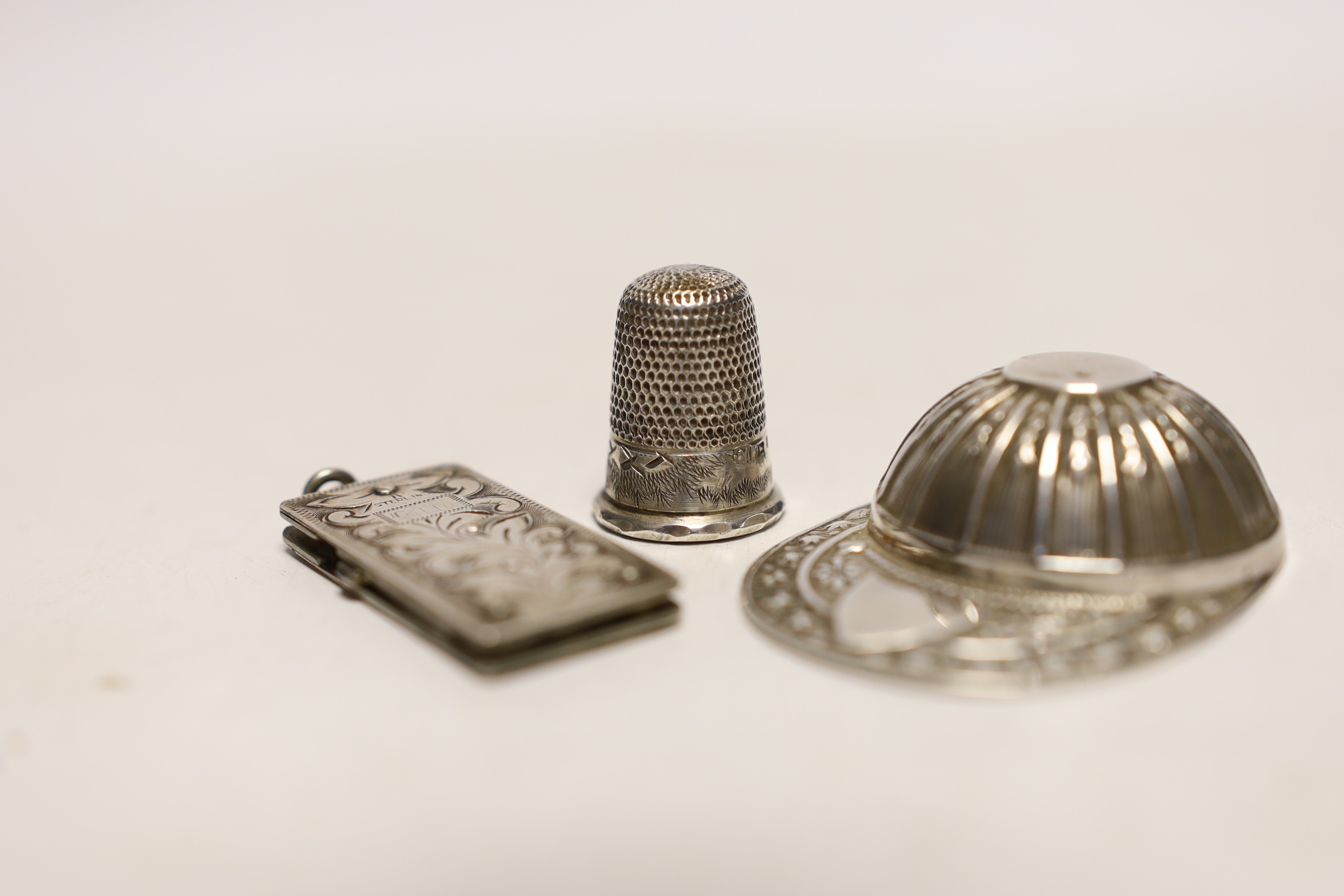 An unmarked white metal caddy spoon, modelled as a jockey's cap, 52mm, together with a silver thimble and silver mounted pocket knife.